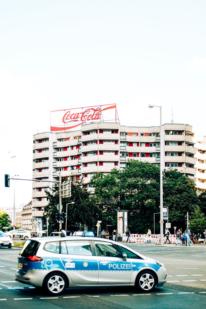 services-01 Coca-Cola sign on building in Berlin with police car at a busy intersection.